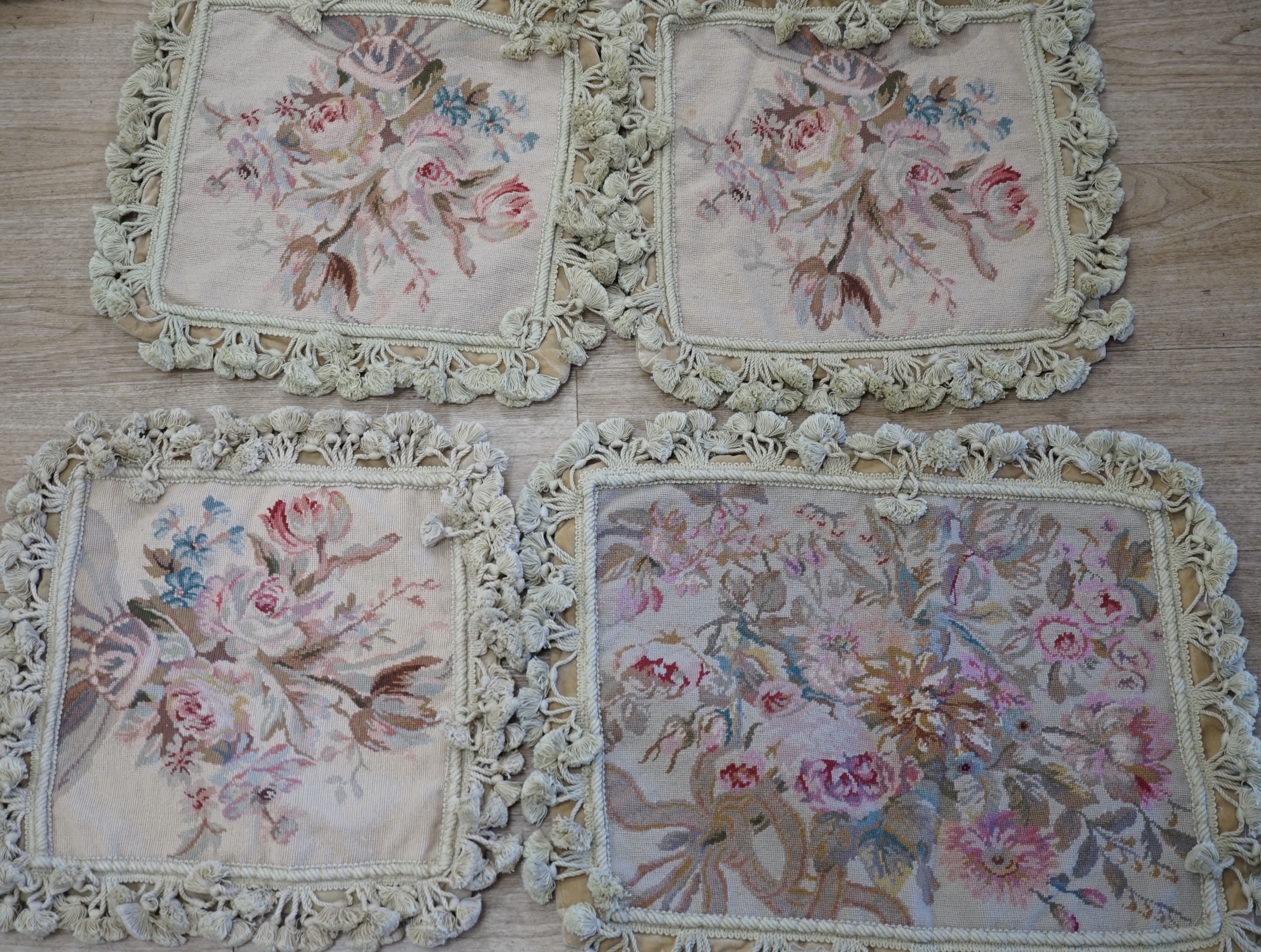 Three small square rose designed wool worked cushion covers and one similar larger cushion cover all with cotton tasselled edging, smaller covers 38cm square, larger cover 38cm x 48cm. Condition - good